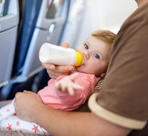 baby-drinking-milk-from-bottle-in-plane - Mustela Australia - 1
